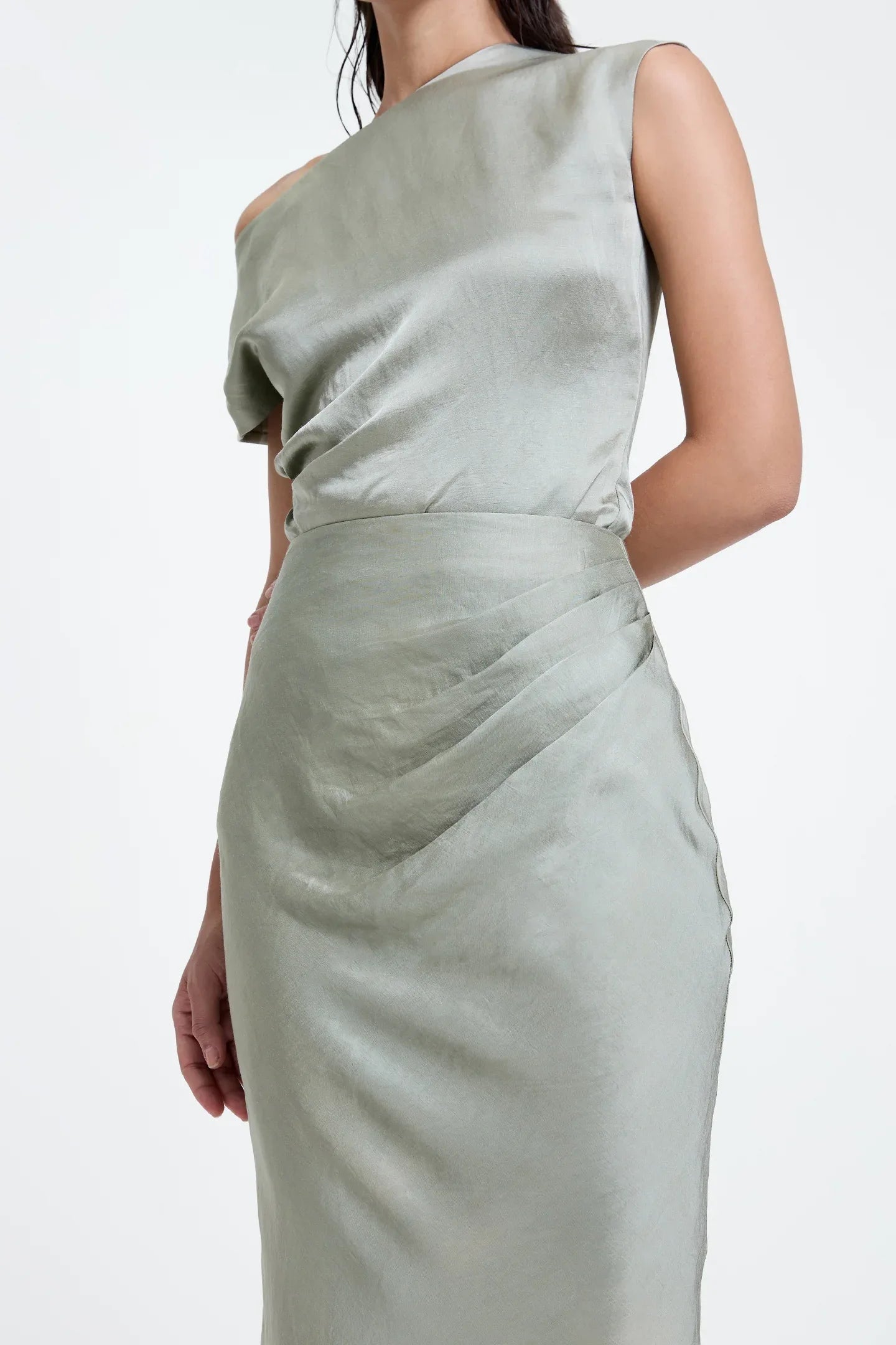 Closeup of a woman wearing a light sage green satin skirt and matching sleeveless top
