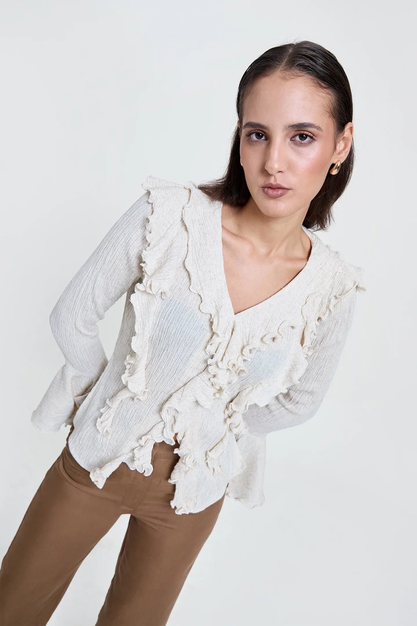 Woman wearing an off-white crinkled ruffle top with V-neck and long sleeves