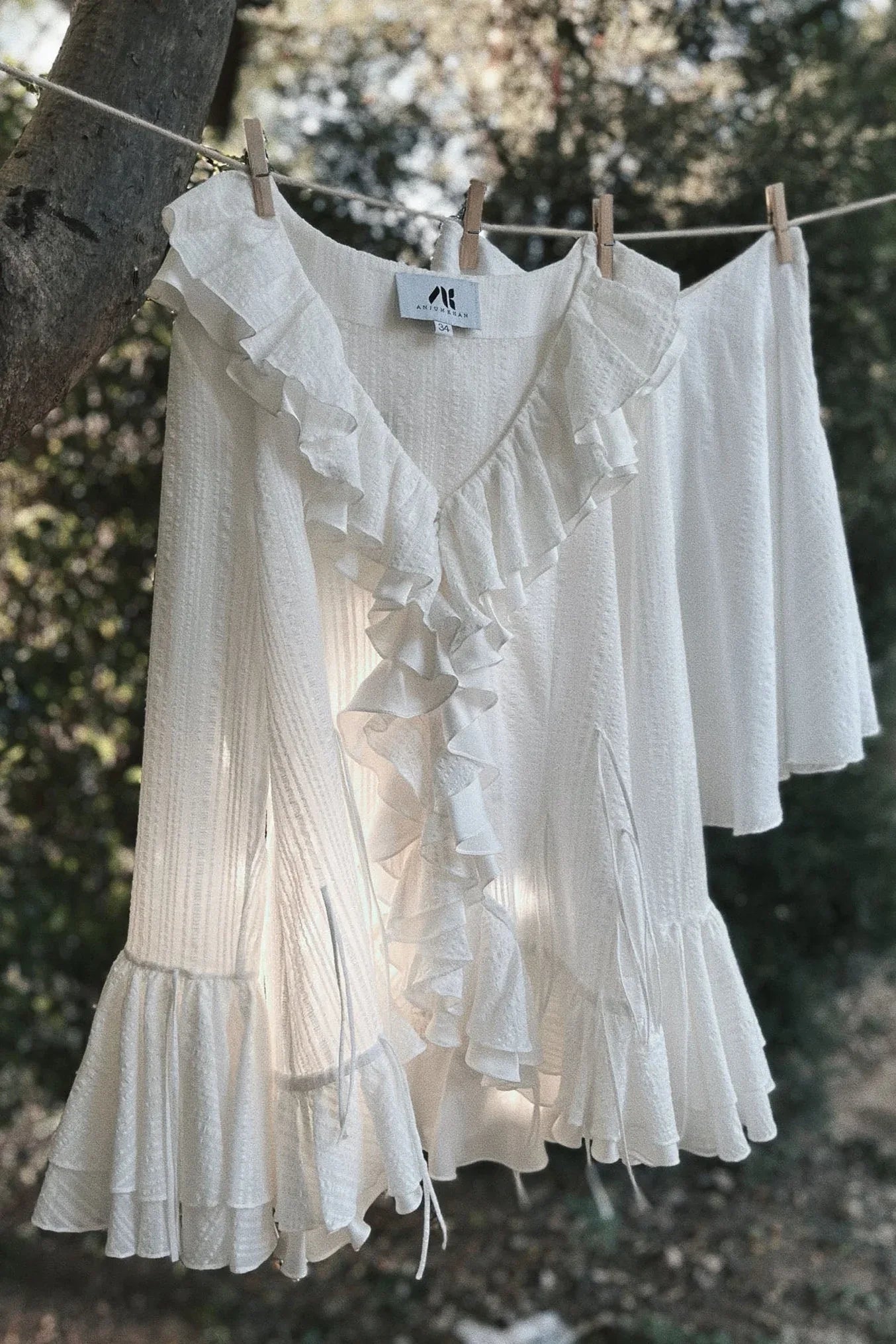 White ruched ruffle dress with flared sleeves hanging outdoors on a clothesline