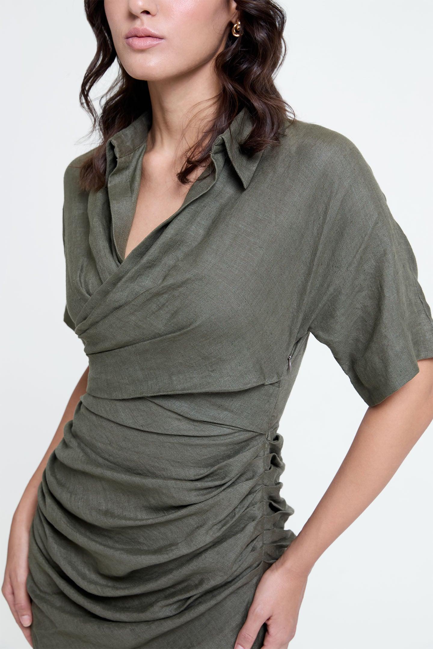 Woman wearing olive ruched dress with short sleeves and draped collar, close-up view
