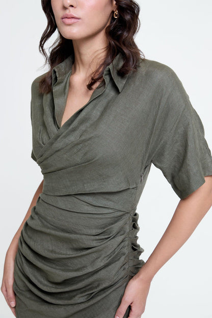 Woman wearing olive ruched dress with short sleeves and draped collar, close-up view