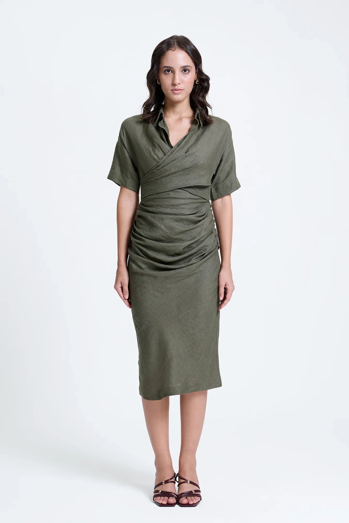 Woman wearing olive green ruched midi dress with short sleeves and wrap front design