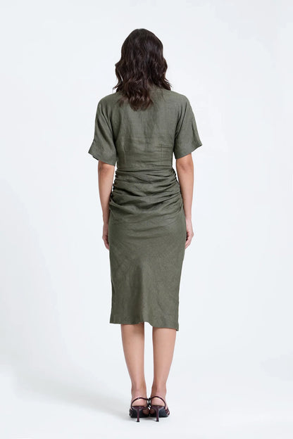 Back view of woman in olive green ruched midi dress with short sleeves and heels